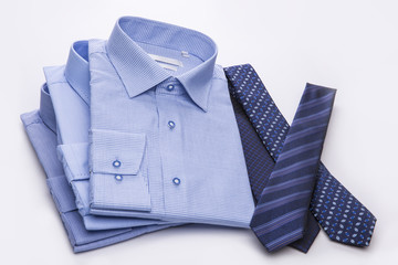 Three blue men's shirts folded in a pack and ties on a white background.