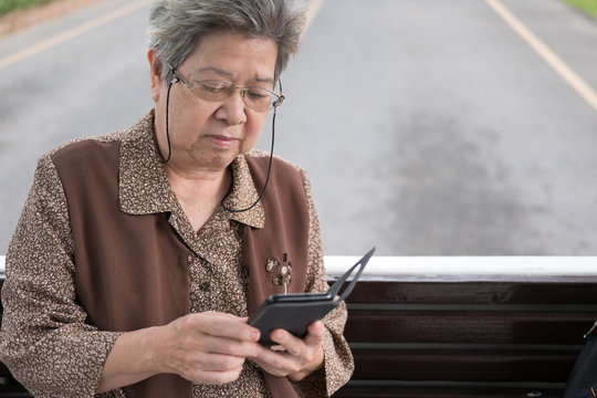 Asian Elder Woman Holding Mobile Smart Phone On Bus. Elderly Senior Female Texting Message, Using App On Tram