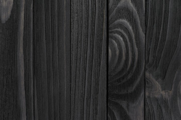 Black Wood Texture. Black stained wooden billboard close-up. Vertical direction cohesive boards. Wavy pattern of wood fibers