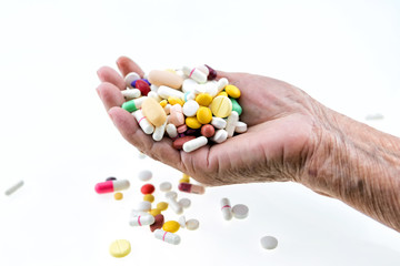 Many multi-colored pills in a Senior's hands on white background; Alzheimer's patients; caring for...