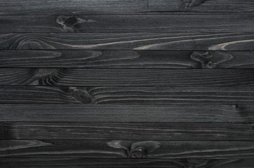 Dark black wood texture background viewed from above. The wooden planks are stacked horizontally