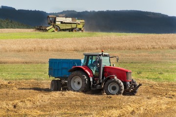 Obraz premium Kombajn zbożowy zbiera dojrzałą pszenicę na farmie w Czechach. Czas zbiorów. Uprawa zboża w gospodarstwie rolnym.