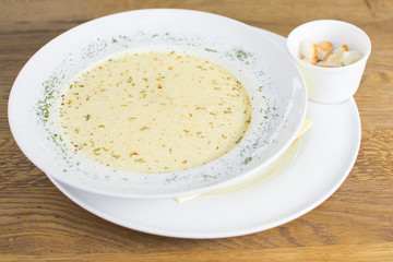 Tomato soup in a black bowl on wooden table. Top view.