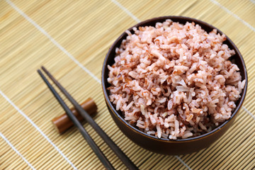 brown rice In the cup and wooden chopsticks. on the table.Concept healthy food