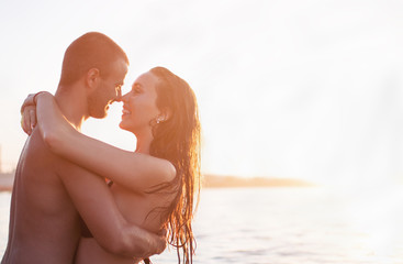 Couple in water at sea, hugging, having fun,at sunset, golden hour