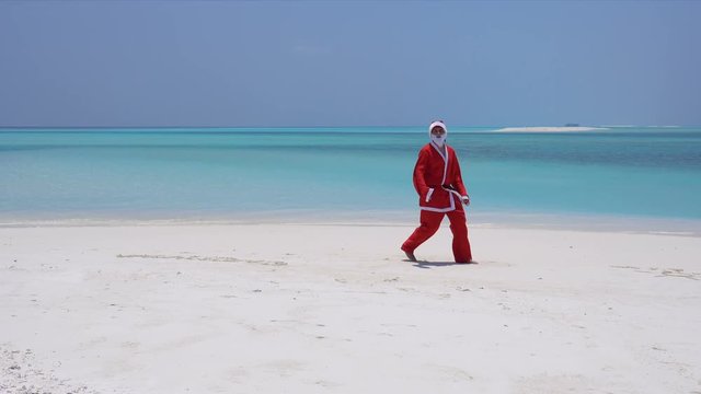 Man in Santa Claus costume on sandy tropical beach. Christmas and New Year celebration on Maldive island
