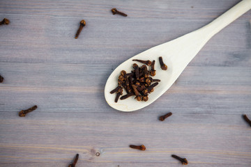 Seasoning cloves on a wooden spoon, background