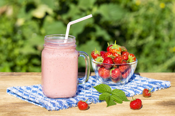 Strawberry, raspberries and banana juice smoothie shake in glass, outdoors, close up