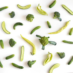A composition of fresh vegetables: green pepper, broccoli, cucumbers on a white background. Food pattern background. Healthy food concept. Top view, flat lay.