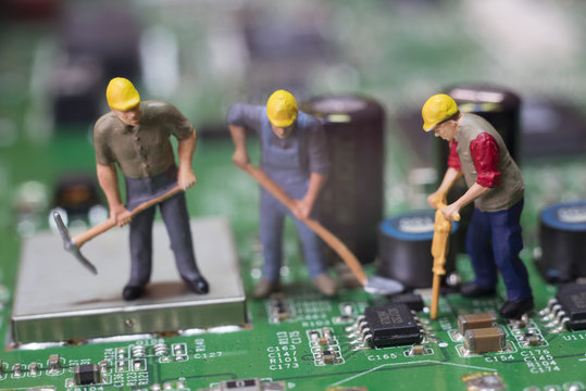 Miniature Workers On Top Of A Circuit Board