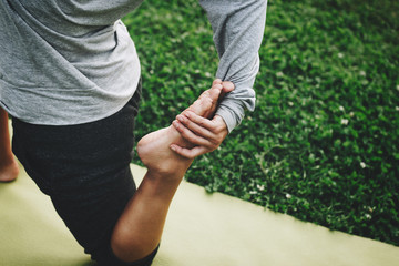 Young woman practicing yoga in a city park on a green lawn on outdoors. Calmness and relax. Asana close-up