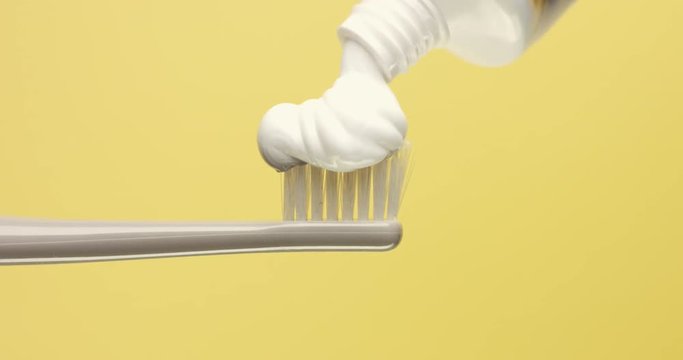 closeup of tooth brush and a tooth paste pouring on it