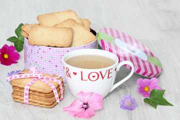 Mug of tea with biscuits and summer flowers 