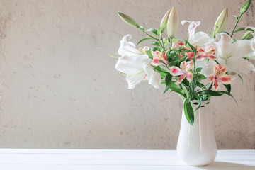 Fototapeta na wymiar beautiful white lily in vase on background old wall