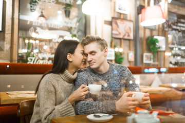 Young affectionate couple relaxing in cafe by cup of coffee