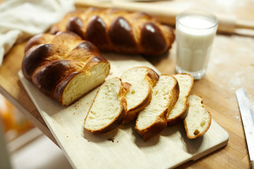 Fresh sliced bread on wooden board and glass of fresh milk near by