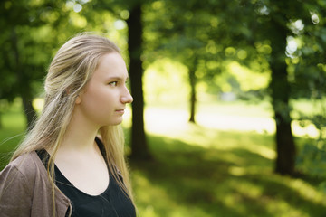 teen girl portrait in green park in sunny summer day