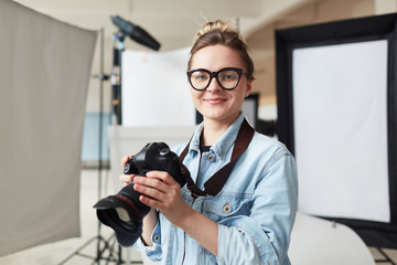 Pretty girl with photocamera shooting in her own photostudio
