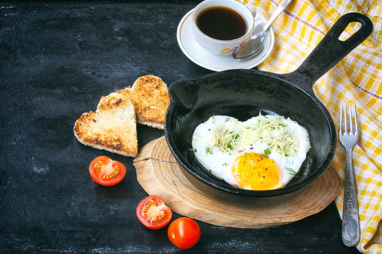 Fried eggs in frying pan, cherry tomato, cup of coffee