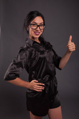 Young happy woman portrait of a confident businesswoman showing by hands on a black background. Ideal for banners, registration forms, presentation, landings, presenting concept.