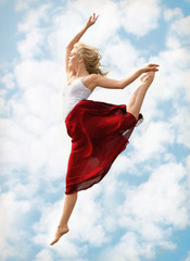 Beautiful passionate female dancer outdoors against blue sky