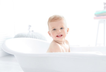 Little baby boy washing in bathtub at home