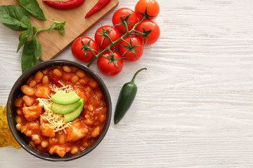 Bowl with delicious turkey chili on wooden background