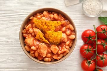 Bowl with delicious turkey chili on wooden background