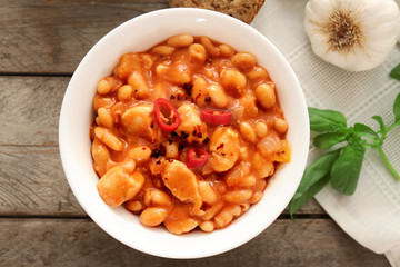 Bowl with delicious turkey chili on wooden background
