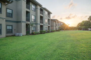 View from grassy backyard of a typical apartment complex building in suburban area at Humble, Texas, US. Dramatic sunset cloud with warm light. © trongnguyen