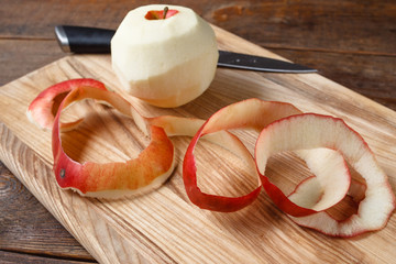 Single red apple paring by knife. Close up fresh fruit lay on wooden desk. Healthy food, dietary,...