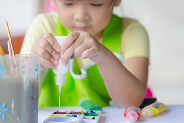 Asian girl hold color tube for painted on plaster doll