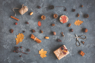 Autumn composition. Gift, autumn leaves, cinnamon sticks, anise stars, pine cones on black background. Flat lay, top view
