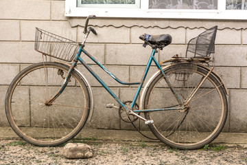 Old bicycle with a makeshift basket and a makeshift seat for the passenger on the trunk
