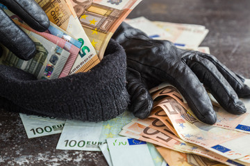 Quick loot in the store. Thief' s hands in black leather gloves stealing a money and putting it in...