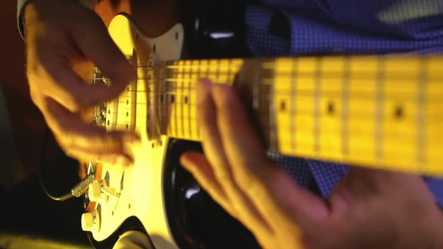 Guitarist plays heavy metal by electric guitar at the dark record studio