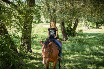 Fototapeta premium young beautiful brunette girl riding horse outdoor