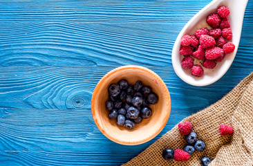 Paspberry and blueberry for preparing jam on blue wooden background top view copyspace