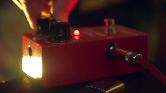 Musician plays by overdrive pedal at the club concert close-up