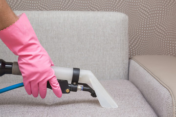 Sofa chemical cleaning with professionally extraction method. Hand in rubber protective glove...