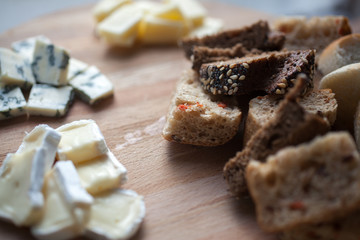 Cheese DorBlu, brie and cheddar and bread on wooden plate