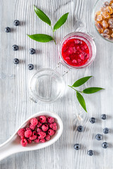 Raspberry jam in glass jar on grey wooden background top view