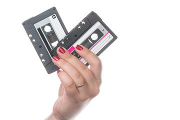 Female hand with red nails holding two retro audio cassette tapes isolated in white background.