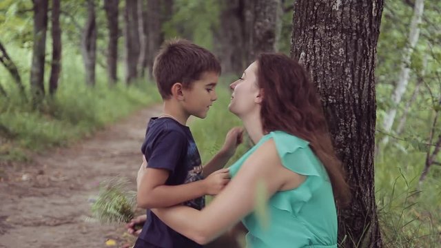 A boy gives a happy mother flowers hugging and kissing her