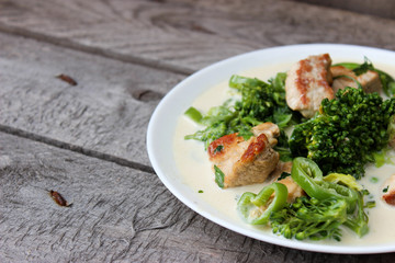Nutritious dish of roasted pork fillet, green pepper, greens, broccoli in cream