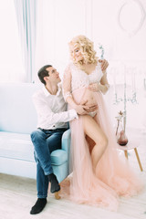 Fototapeta na wymiar Pregnant young girl in a light orange dress with her husband
