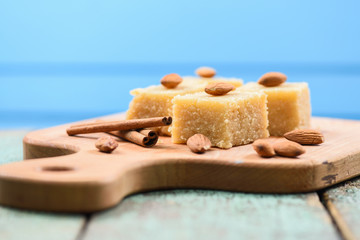 Indian traditional dessert, halva wih cinnamon and almonds served on wooden board on blue background copyspace