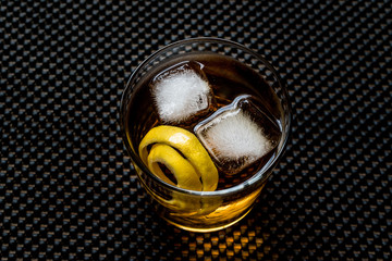 Highball cocktail with lemon peel and ice.