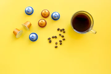 Papier Peint photo Lavable Bar a café Beverage capsules for coffee mashine near coffee cup and grains on yellow background top view copyspace