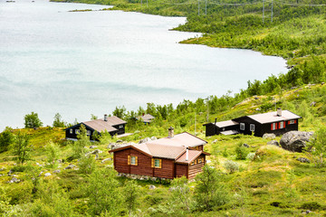 Group of small lakeside cabins in mountainous landscape. Location Hardangervidda in Norway.